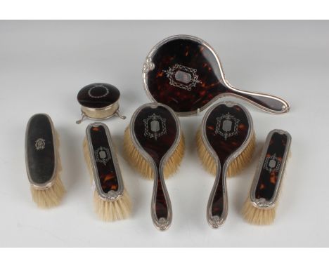 A George V silver and tortoiseshell five-piece dressing table set with piqué inlaid decoration, comprising hand mirror, two h