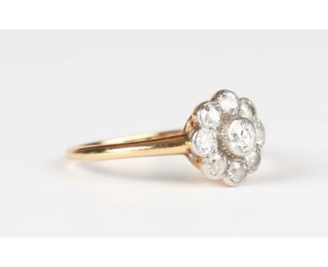 A gold, platinum and diamond cluster ring, collet set with the principal cushion cut diamond within a surround of eight small