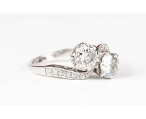 A white gold and diamond ring, claw set with the two principal circular cut diamonds in a crossover design between diamond se