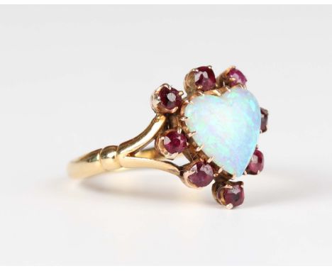 A gold, opal and ruby heart shaped cluster ring, claw set with a heart shaped opal within a surround of eight cushion cut rub