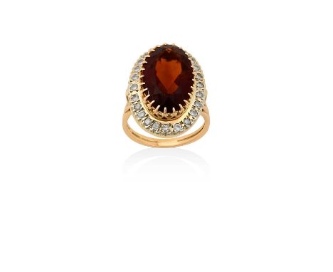 A Citrine and Diamond Cluster Ring, the central raised oval cut citrine in yellow claw settings, within a border of round bri