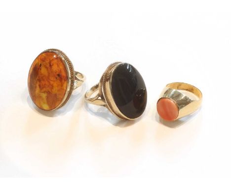 A 9 Carat Gold Amber Ring, finger size N; A 9 Carat Gold Onyx Ring, finger size M; and A Coral Ring, unmarked, finger size K 