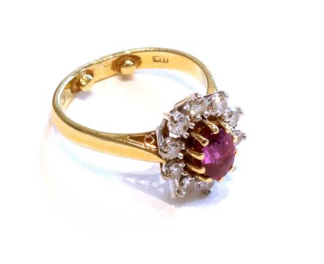 An 18 Carat Gold Ruby and Diamond Cluster Ring, the oval cut ruby in a yellow claw setting, within a border of round brillian