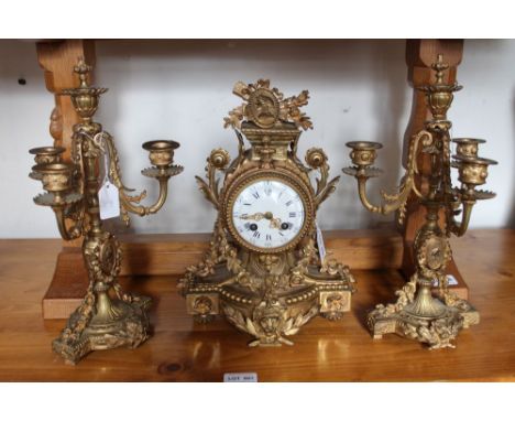 A 19th century French clock garniture, gilt metal framed, the clock with floral swags, mask and medallion, fitted an eight da