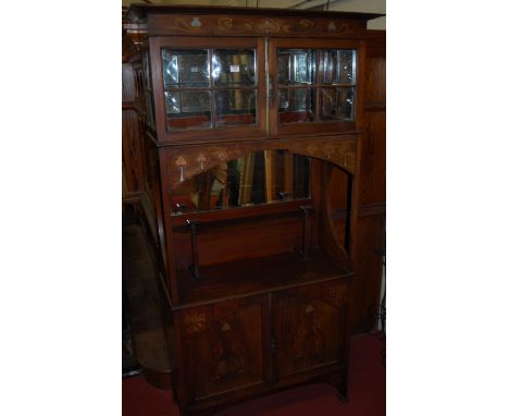 An Art Nouveau Glasgow School style mahogany and inlaid side cabinet, having twin door glazed upper compartment with mirrored