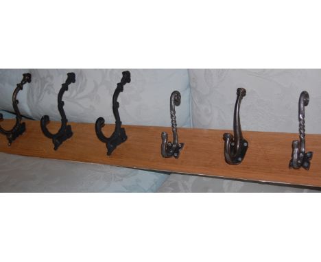 A light oak backed wall mounted coat rack with various iron hooks
