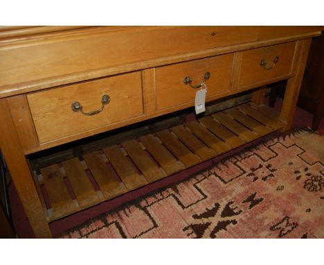 A joined light oak dresser base having three short drawers over laddered platform undertier