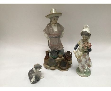 Three assorted Lladro ceramic figures comprising a Mexican ceramic street vendor, a girl holding a bunch of flowers and a cat