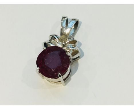 An 18ct white gold pendant set with a large Ruby, measuring 13mm, and a small round diamond to the centre of the bow design, 