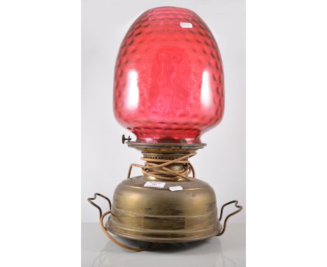 Brass oil lamp, dimpled cranberry coloured shade with a cast metal dome, 60cm.