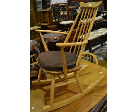Ercol beech rocking chair, bar back with turned spindles, open arms, turned legs joined by rails, width 64cm, height 86cm.