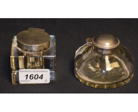 An Edwardian silver-mounted clear glass square inkwell, hinged cover. 5.5cm wide, London 1902; another, circular (2)