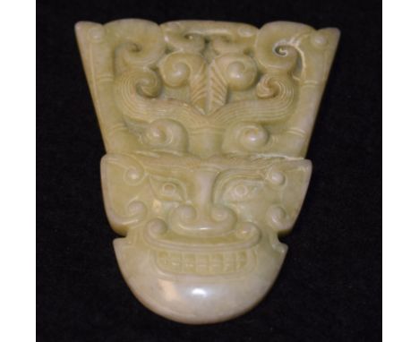 A Chinese pale green jade pendant, boldly carved as a demonic immortal, loop suspension hole, 7.5cm long, 6.5cm wide 