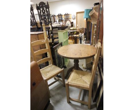 Pine circular dining table on tripod base together with two ladder back dining chairs with string seats