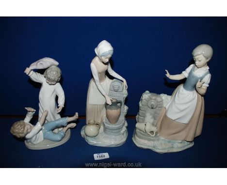 A Nao figure of two young children having a pillow fight, a girl fetching water from the well and a Nao figure of a lady at t