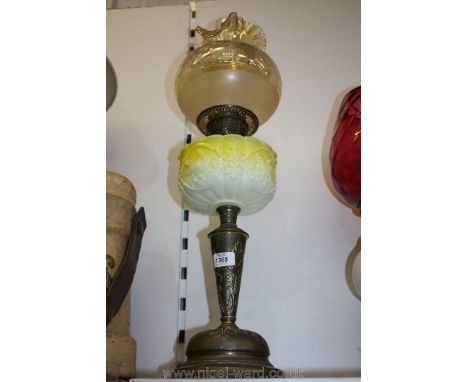 A Brass Oil Lamp with embossed leaves to the stem, yellow reservoir embossed with birds and flowers and wavy edged glass shad