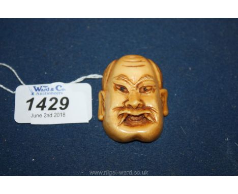A Meiji period carved Demonic Oni Mask Netsuke complete with fangs and two Himatoshi at the back.