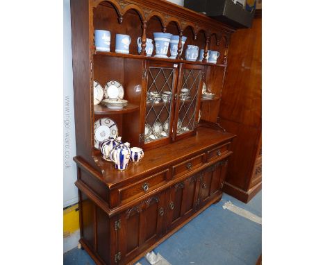 A reproduction Oak Dresser having plate rack with three shelves and two small leaded glazed doors, over the base with three d