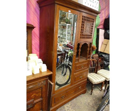 An Oak Moorish Compactum by Liberty & Co., circa 1890, having long bevel plated mirrored door to one side, upper single panel