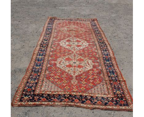 A vintage Persian Rug. three light medallions in geometric pattern border, some damage, 131" long x 55" wide