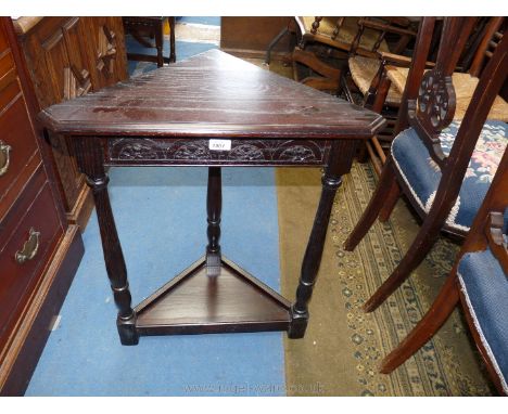 A Jaycee Oak Corner Table, having triangular top, carved frieze, on turned legs with lower shelf