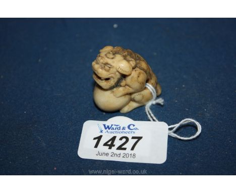 A late Edo period Japanese Netsuke of a Karashishi with large ball between his paws and a small free moving ball in his mouth