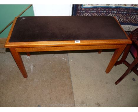 A modern, light, hardwood Duet Stool with brown fabric seat on square legs.