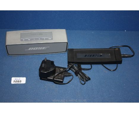A Bose Soundlink Mini Bluetooth Speaker with charging cradle and mains adaptor.