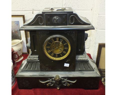 A large black slate striking mantel clock of architectural form, with visible escapement and applied metal mounts, 46cm high,