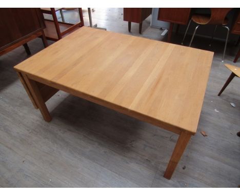 A Danish light oak finish coffee table with drop flap to one end, raised on square legs.  111cm x 75cm x 53cm