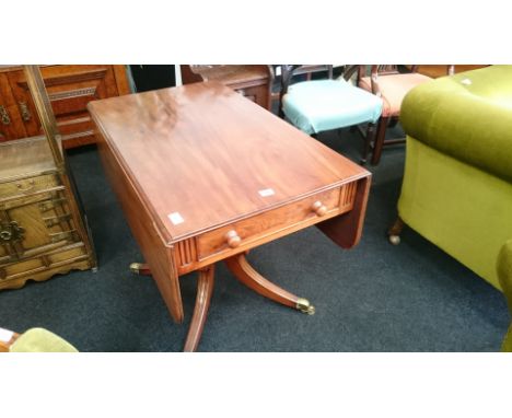 A mahogany sofa table with single drawer resting on outswept supports with brass castors.