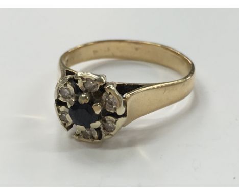 A yellow metal sapphire and diamond cluster ring.