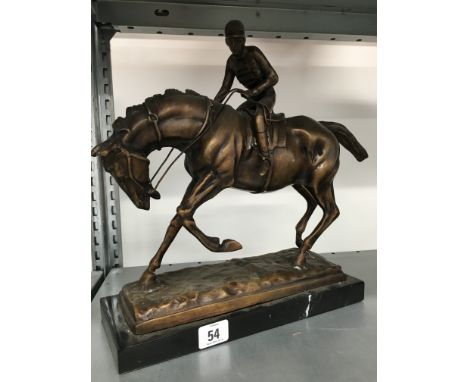 A bronzed model of a horse and jockey on black marble base.