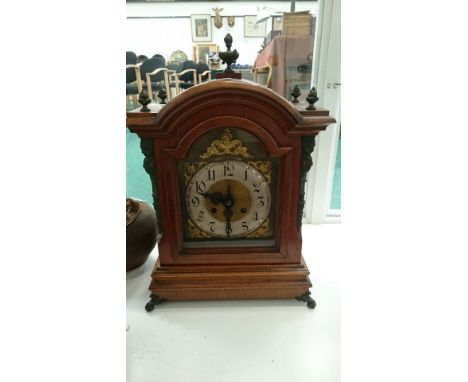 A German oak and mahogany cased bracket clock with nickel silver dial, brass Chapter rings, brass finials and brass corner su