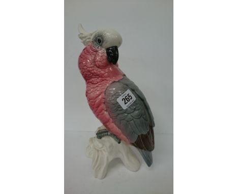 A Beswick china model of a pink parrot on treestump with grey claws.