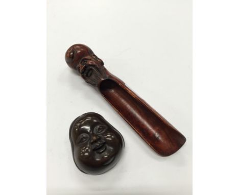 A Chinese hardwood apple corer with carved deity face finial and a carved hardwood Koh theatre mask netsuke.