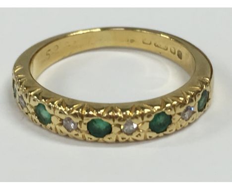 A three stone emerald and diamond half eternity ring set in 18 carat gold (2.9 grams).