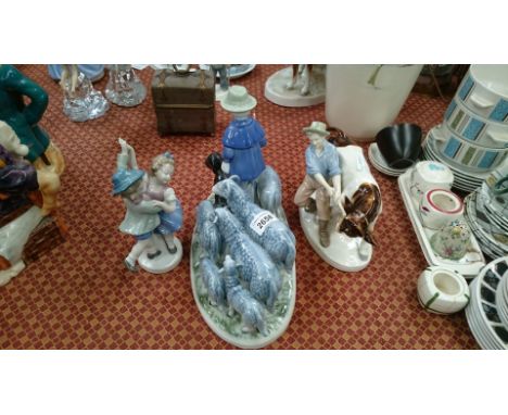 A West German glazed model of a shepherd with sheep, a similar model of two children dancing and a young boy holding a steer.