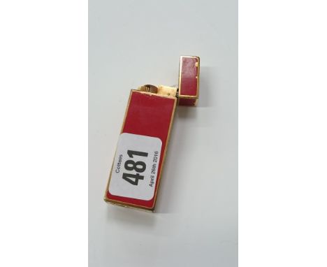 A Cartier Must cigarette lighter in a red lacquered case, Serial No. 380911 (slight wear).