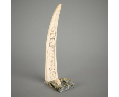 Inuit walrus and stone cribbage board. Comprised of a carved walrus with incised details and drilled cribbage holes, along th