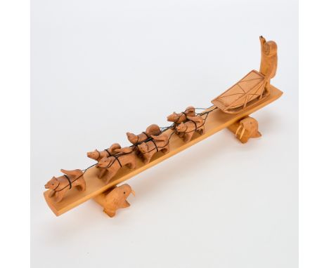 Paul Imana carved wooden sculpture depicting an inuk and sled dog team comprised of a sled and seven dogs. Mounted on a recta