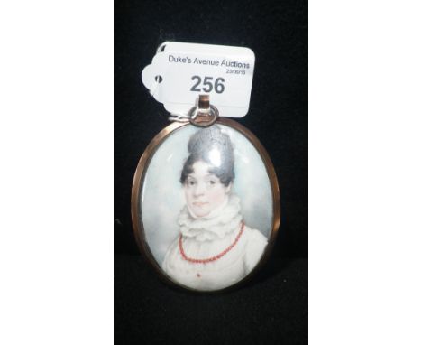 A 19th century painted oval miniature portrait of a lady wearing a white dress and wearing an orange bead necklace in a gilt 