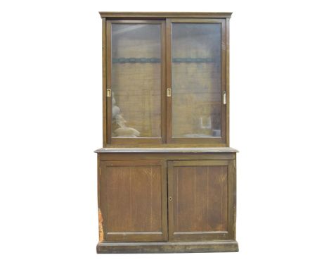 A late Victorian stained hardwood glazed cabinet on cupboardWith a moulded cornice above two sliding glazed doors each with b