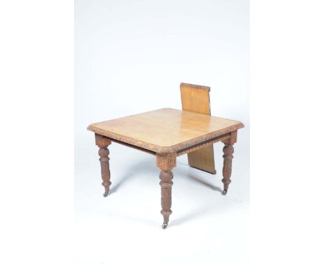 An early 20th Century light oak extending dining tableWith canted corners and a carved border above blocks carved with flower