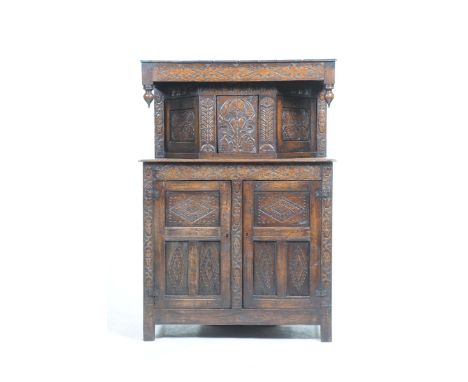 A 17th Century style carved oak court cupboard,Having a board top above a frieze carved with a geometric foliate design over 