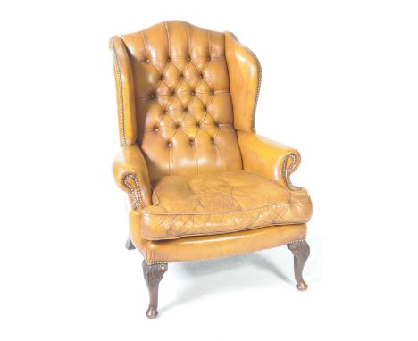 A Georgian style tan leather wingback fireside armchair, 20th CenturyWith a button and studded back flanked by padded wing ba