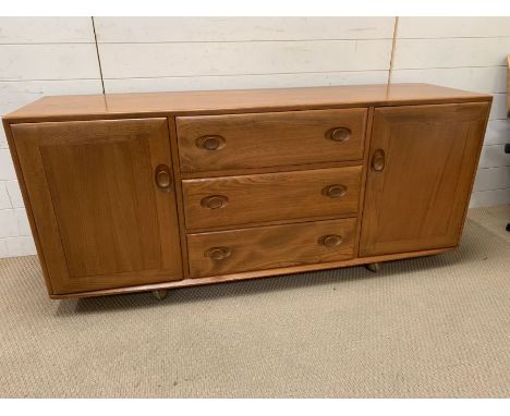 An Ercol blonde sideboard with cupboards to side and drawers to centre (H66cm W156cm D42cm)