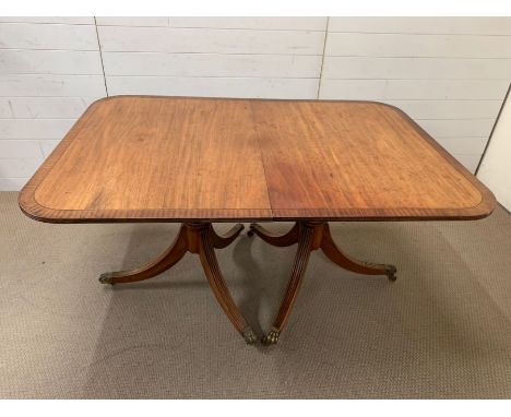 A George III mahogany 2-pillar dining table with rounded corners,crossbanding ebony stringing and 2 extra leaves, on reeded o