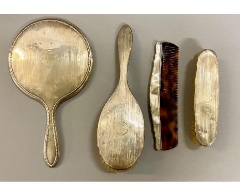 A Four piece silver dressing table set each with a circular cartouche, comprising mirror, hair and clothes brushes and comb.