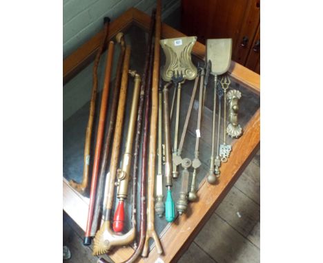 A quantity of walking sticks, walking staffs, brass pumps, brass fire tools etc 